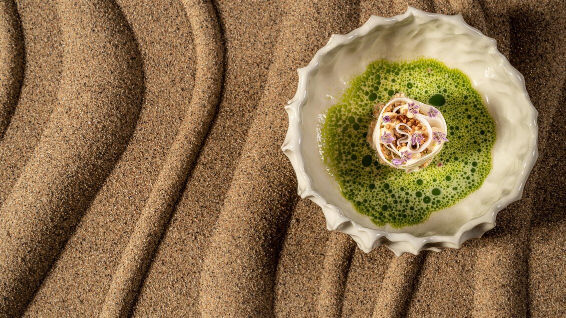 Kreativ angerichtetes Gericht im Restaurant Wörgötter in Ligist mit grüner Sauce, Blüten und knusprigen Elementen | © Die Abbilderei