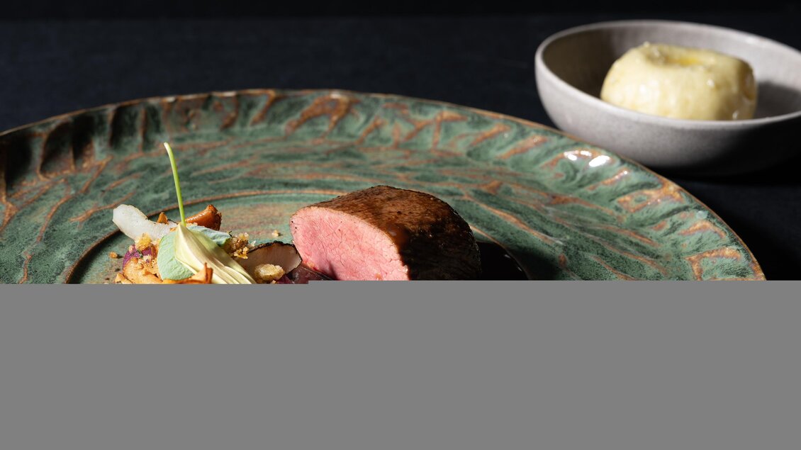 Rosa gebratenes Fleisch mit dunkler Sauce, Gemüse und Kräutern auf einem grünen Teller im Restaurant Wörgötter in Ligist | © Restaurant Wörgötter_Die Abbilderei