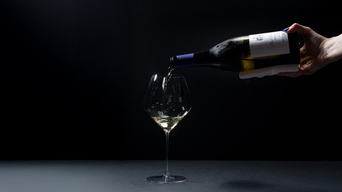 Eine Hand schenkt Weißwein aus einer Flasche in ein Weinglas ein. Die Aufnahme entstand im Restaurant Wörgötter in Ligist | © Restraurant Wörgötter_ die Abbilderei