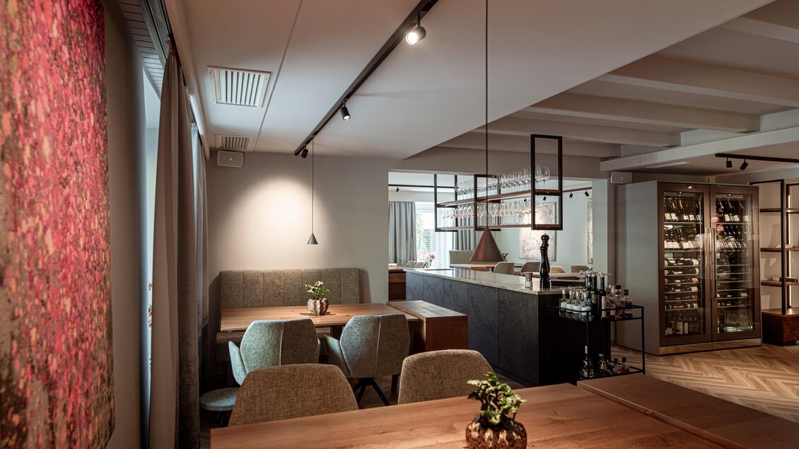 Gastraum im Restaurant Wörgötter in Ligist mit Holztischen, gepolsterten Stühlen, zentraler Theke und Weinschränken | © Die Abbilderei