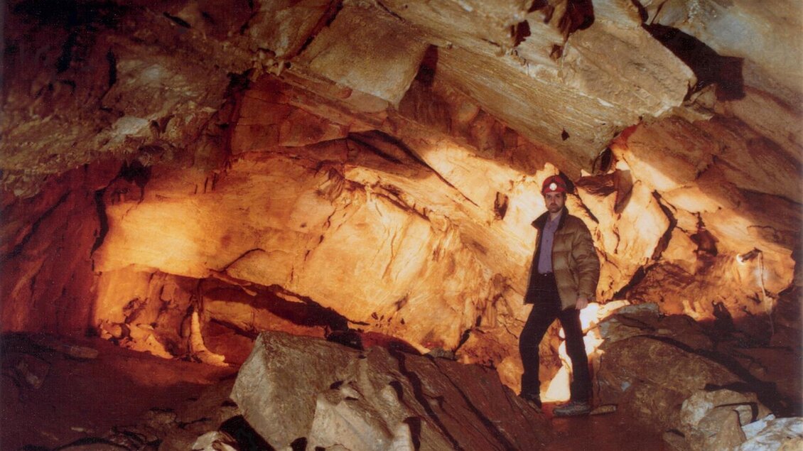 Eine Person steht in einer Höhle mit beeindruckenden Steinformationen. Das Licht, das die Wände beleuchtet, schafft eine mystische Atmosphäre. | © Fritz Bayerl