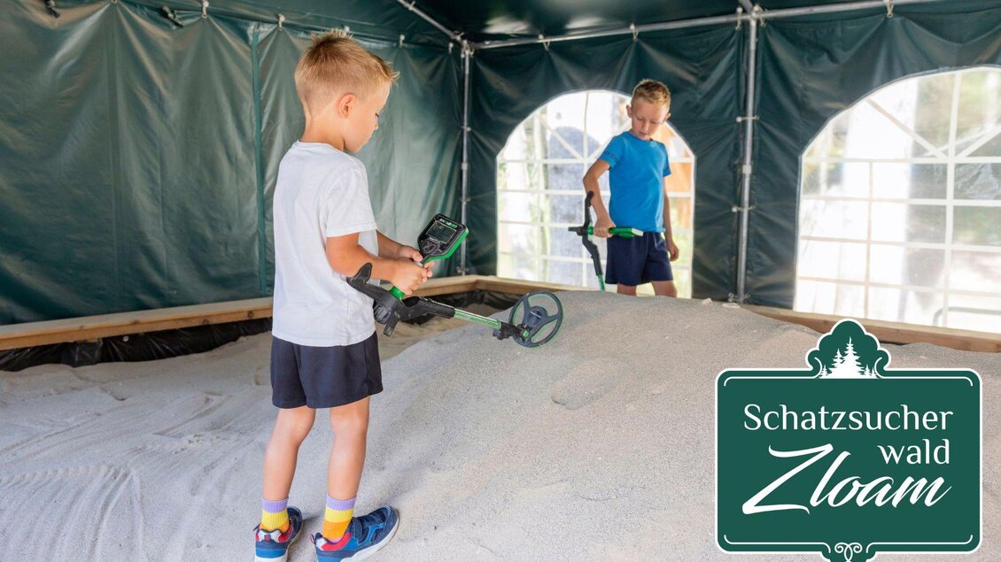 Zwei Kinder stehen in einem Zelt und suchen mit Metalldetektoren im Sand nach Schätzen. Es ist eine unterhaltsame Aktivität für Kinder. | © www.zloam.at