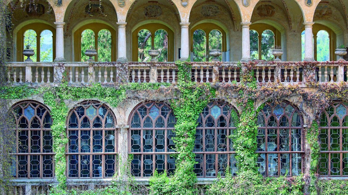 Ein verlassenes Gebäude mit großen Fenstern und Bögen. Überwuchert mit Pflanzen, zeigt es den Verfall der einst prächtigen Architektur. | © Robyn Lea
