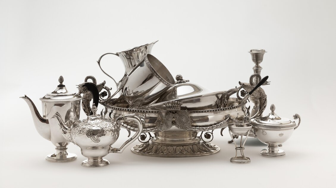 Ein Set aus silbernem Geschirr mit verschiedenen Teekannen, einer Schüssel und einem Kerzenständer. Die Stücke weisen kunstvolle Verzierungen und elegante Formen auf. | © Lipp Zahnschirm