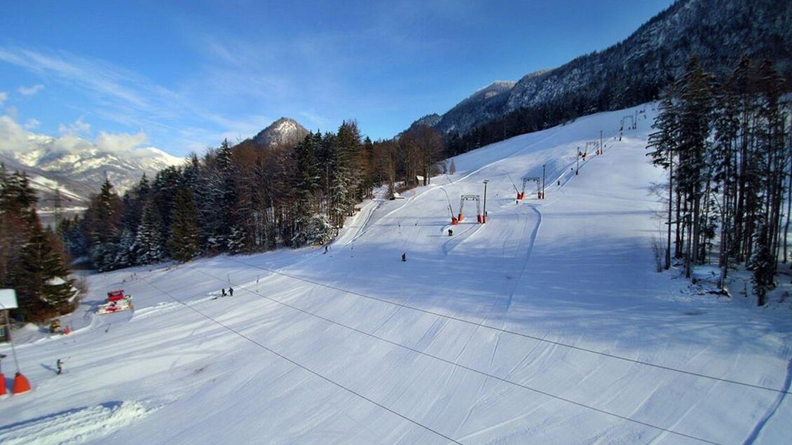 Eine verschneite Skipiste mit zahlreichen Skiliften im Hintergrund. Die Umgebung ist von hohen, grünen Bäumen und Bergen umgeben. | © Gottfried Wimmer