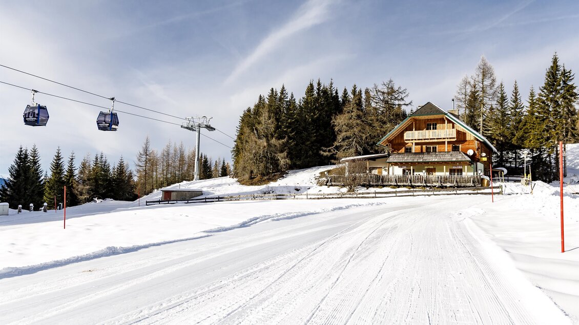 Eine idyllische Berghütte im verschneiten Winterwald. Skilifte schweben über die ruhige Landschaft. | © Tourismusverband Murau