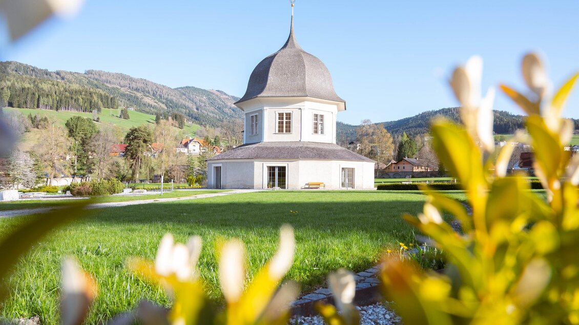Ein schönes, rundes Gebäude mit einer spitzen Kuppel umgeben von Wiesen und Bergen. Der Himmel ist klar und blau. | © TVB Murau