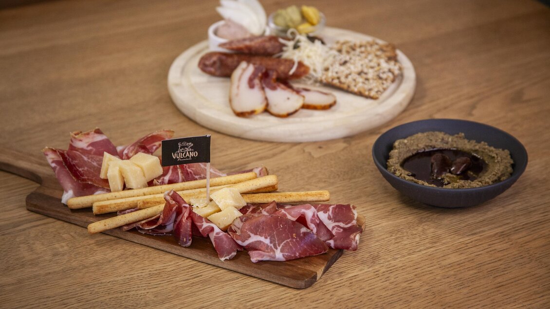 Ein appetitliches Fleisch- und Käsebrett mit verschiedenen Wurstsorten und Käse. Dazu gibt es einen Dip in einer Schale und knusprige Stangen. | © Vulcano