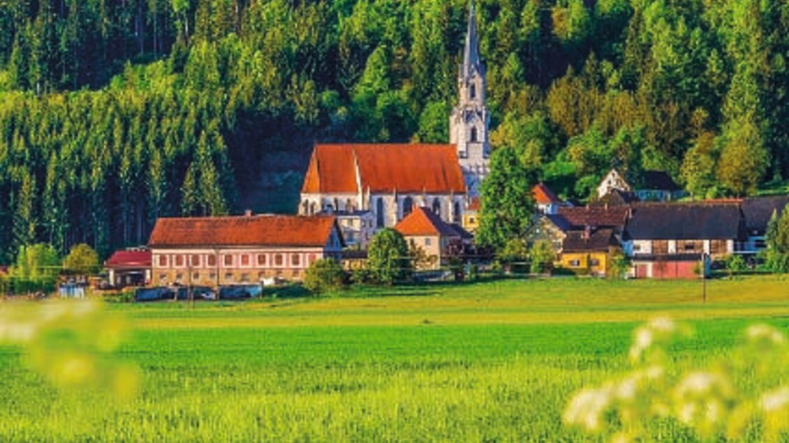 Ein malerisches Dorf mit alten Gebäuden und einer Kirche auf einem Hügel. Umgeben von grünen Feldern und Wäldern. | © Erlebnisregion Murtal