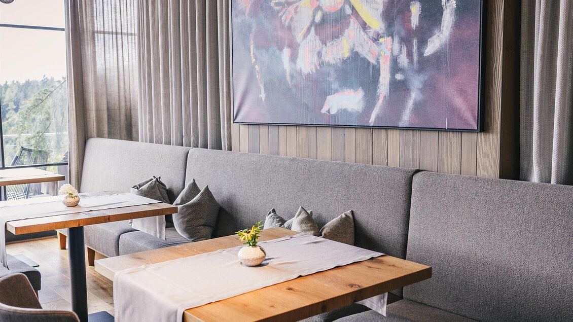 Ein modernes Restaurant mit gemütlichen Sitzplätzen und einem großen, farbenfrohen Kunstwerk an der Wand. Die Atmosphäre ist einladend und stilvoll. | © Oststeiermark Tourismus