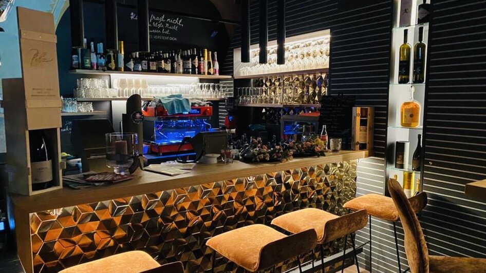 Moderne Bar mit goldener Theke und Getränken in Graz.