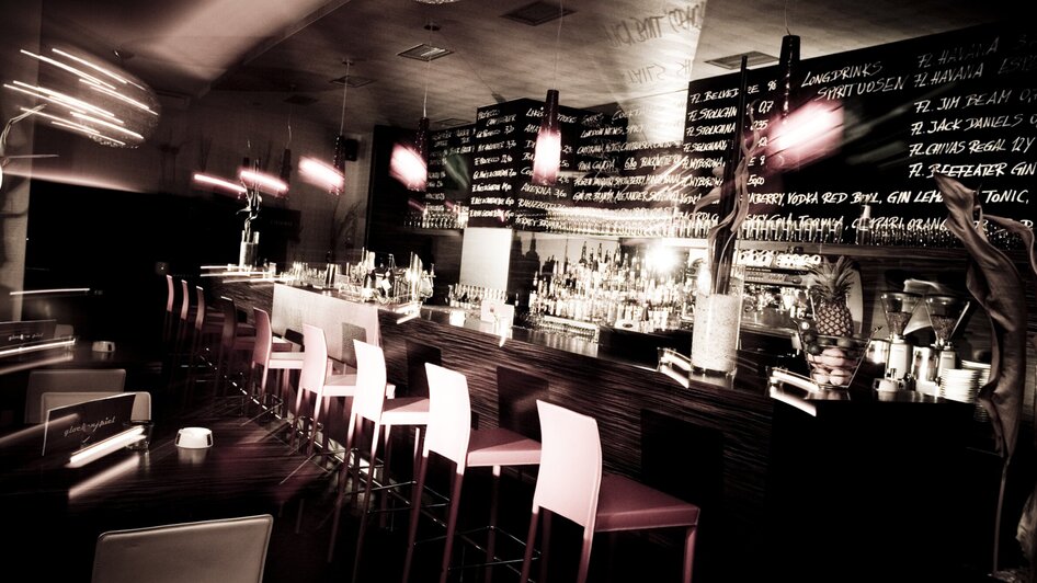 Stylische Bar mit beleuchteten Regalen und stimmungsvollem Ambiente.