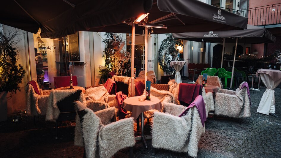 Gemütliche Terrasse eines Cafés mit kuscheligen Stühlen in Graz.
