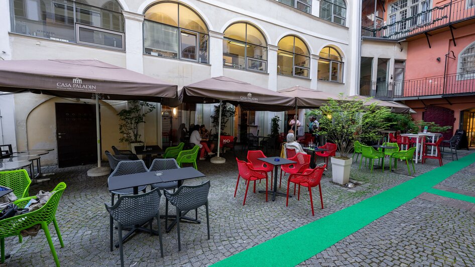 Gemütlicher Innenhof mit bunten Stühlen und Tischen in Graz.