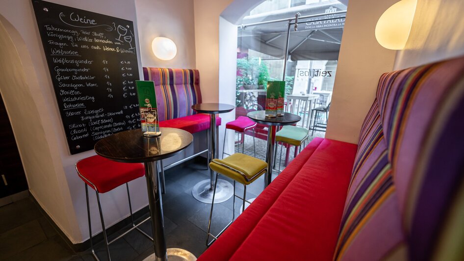 Ein modernes Café in Graz mit bunten Stühlen und einer Weinkarte.