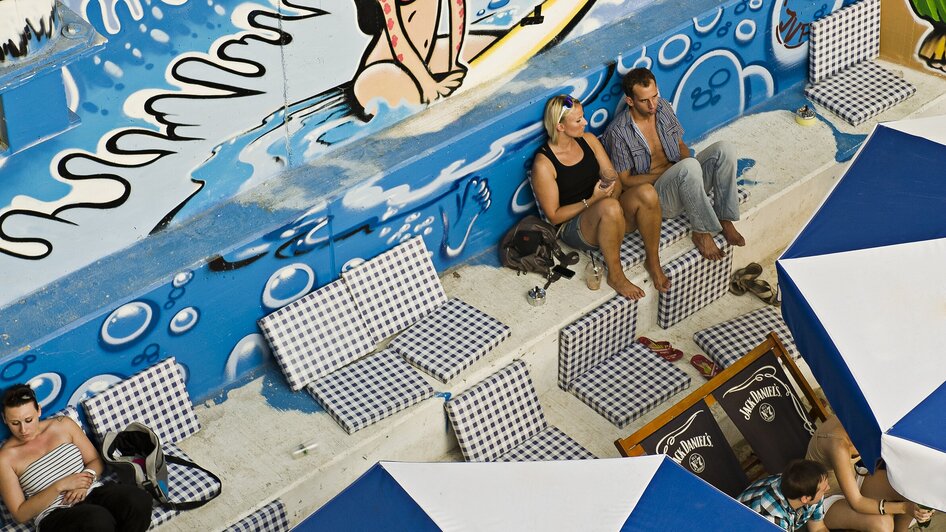 Blick auf eine Strandbar mit Graffiti und Sonnenliegen. | © Toni Muhr