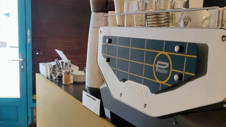 Theke eines Cafés mit Kaffeemaschine und Gläsern.