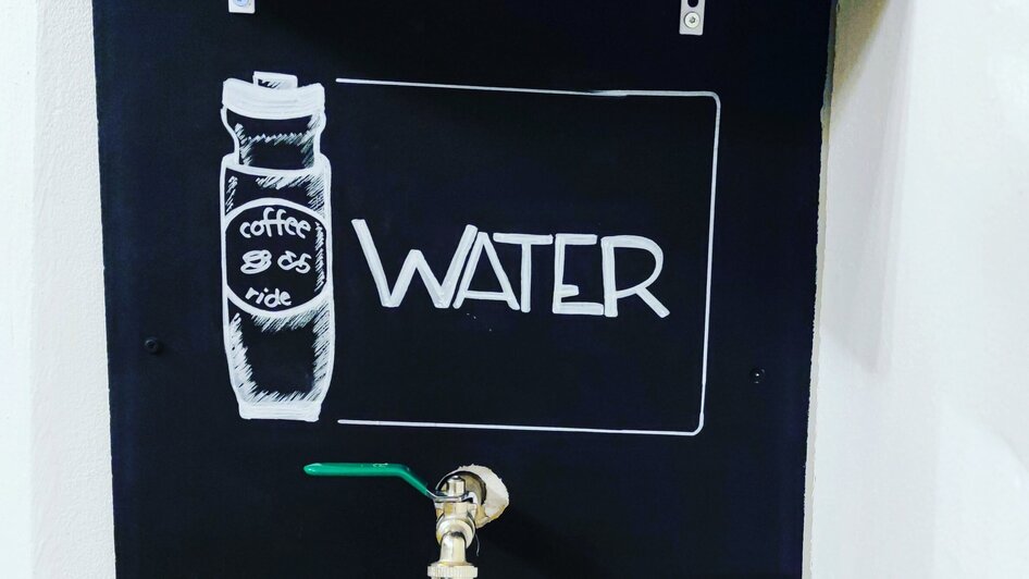 Wassertankstelle mit Gläsern und Beschriftung 'WATER'.