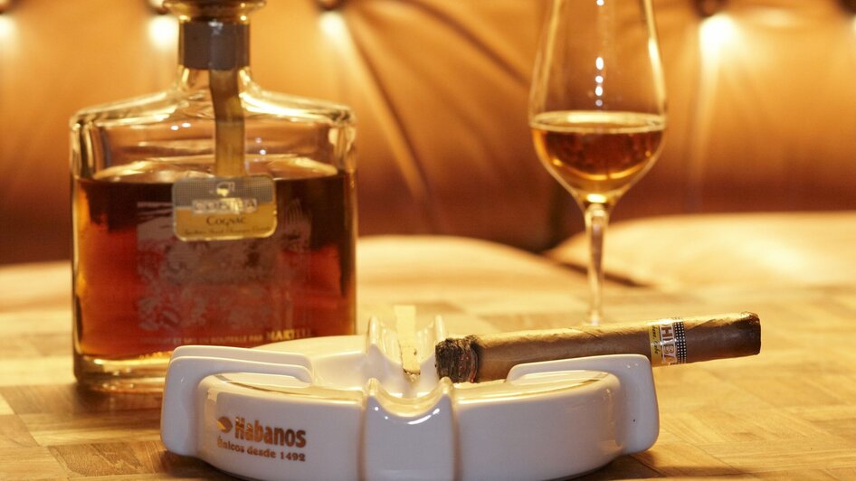 Whisky, Zigarre und Glas auf einem Tisch in gemütlicher Atmosphäre.