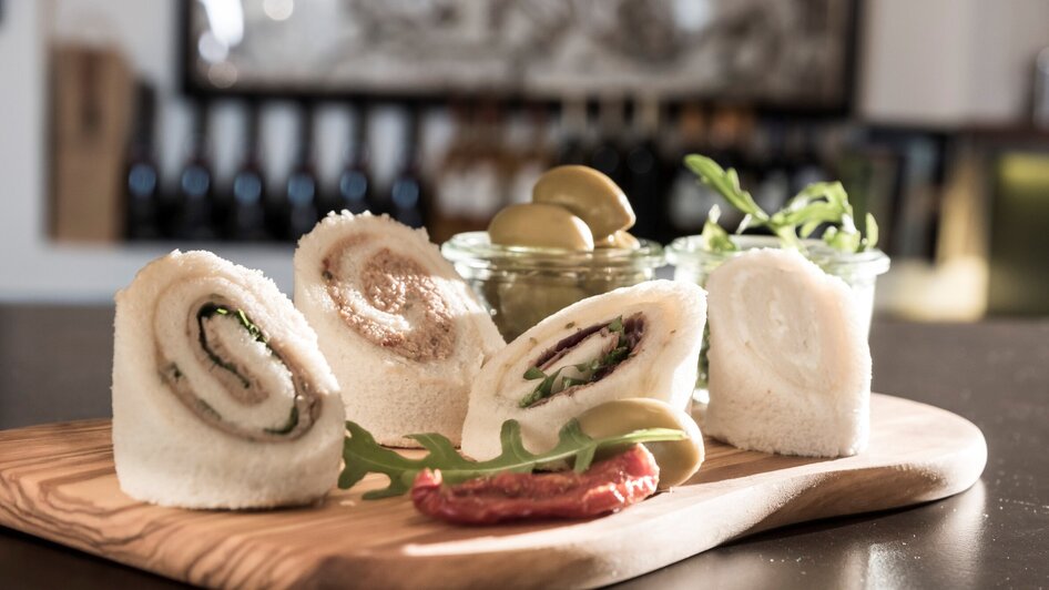 Feine Wraps mit Oliven auf einem Holzbrett.