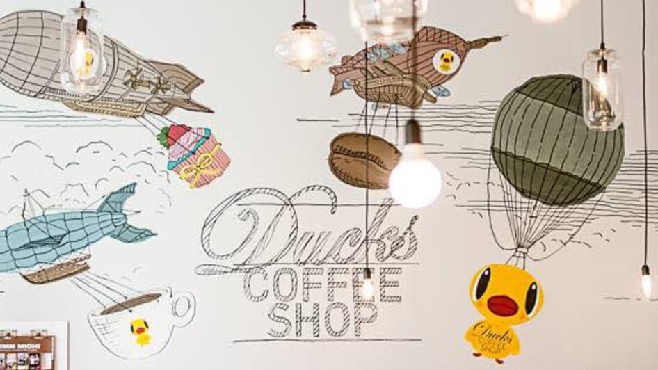 Gemütliche Wandmalerei im Ducks Coffee Shop mit Luftballons und einem Entenmotiv.