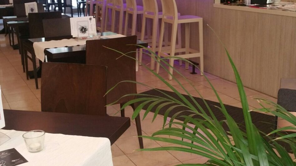 Moderne Restaurantansicht mit Bar und Tischen.