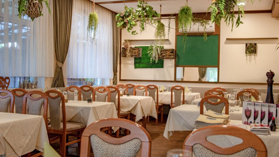 Gemütliches Restaurant mit Pflanzen und gedeckten Tischen.