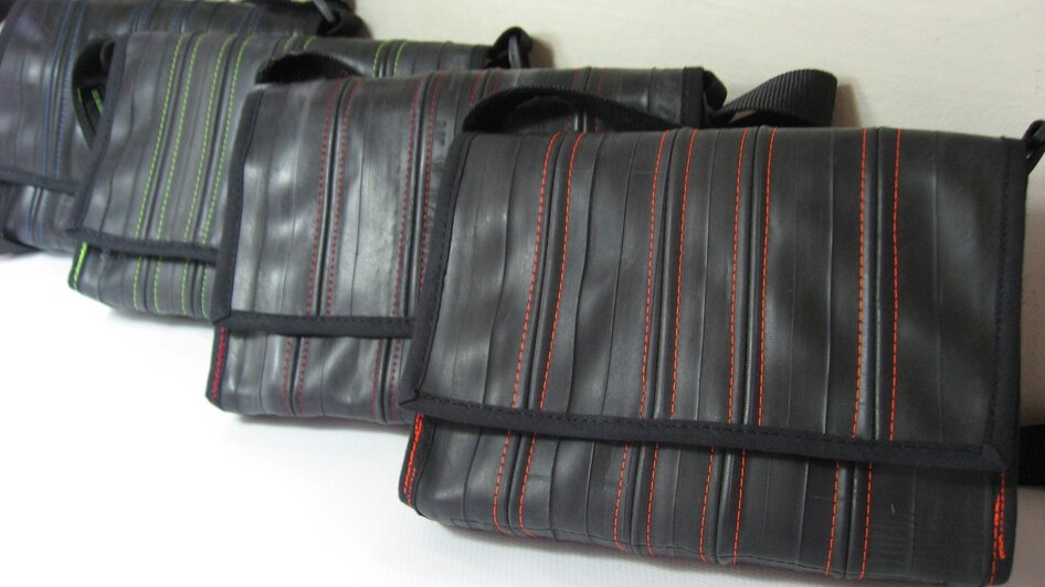 Mehrere Taschen aus recyceltem Material in verschiedenen Farben.