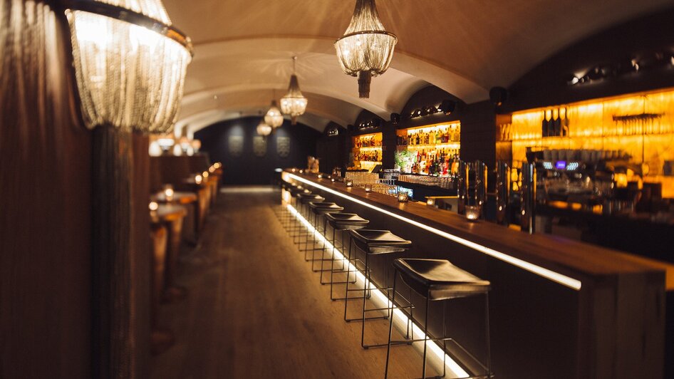 Elegant beleuchtete Bar mit Sitzplätzen und Getränken.