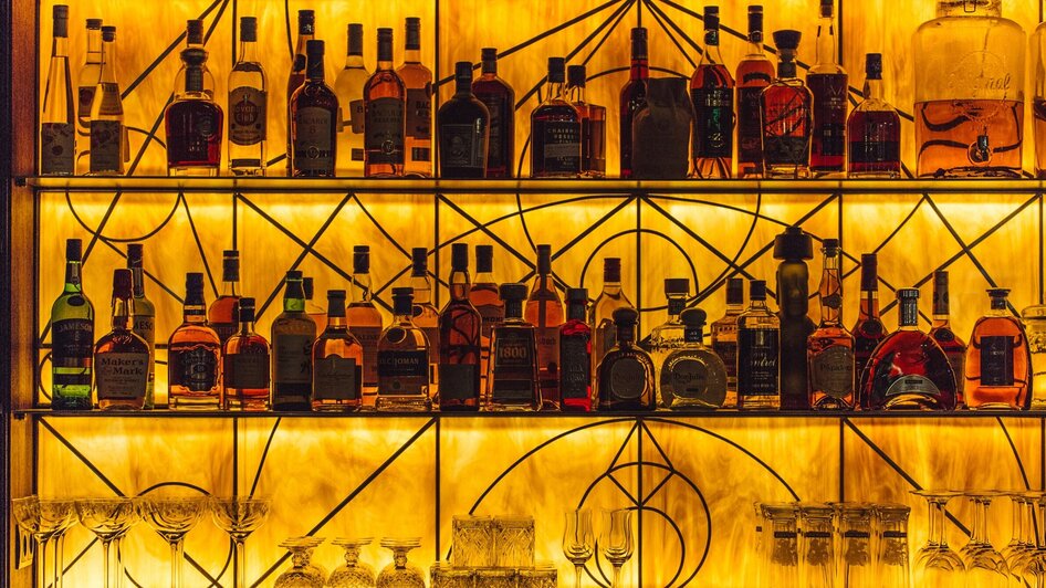 Beleuchtete Spirituosenregale in einer stilvollen Bar.