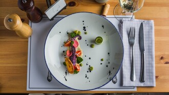 Ein kunstvoll angerichteter Teller mit frischem Fisch und Gemüse.