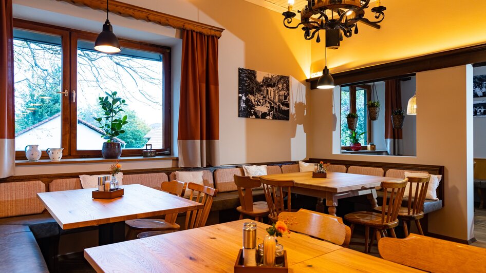 Gemütliches Restaurantinterieur mit Tischen und Stühlen.