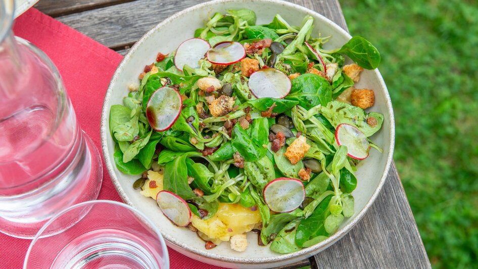 Eine Schüssel frischer Salat mit Radieschen, Croutons und grünen Blättern.