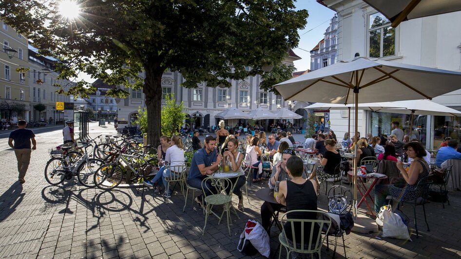 Besucher genießen das Ambiente im Kunsthauscafé in Graz bei Sonnenschein.