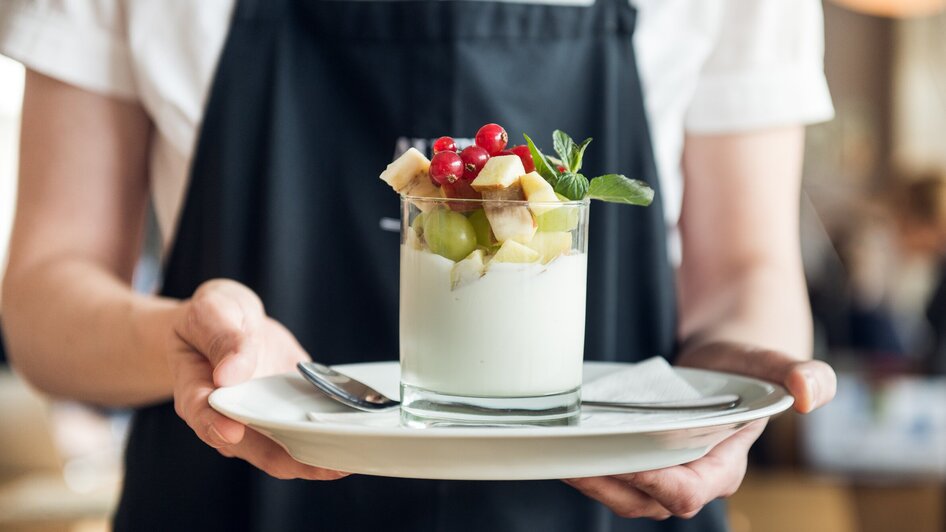 Ein Kellner serviert ein Dessert mit frischen Früchten.