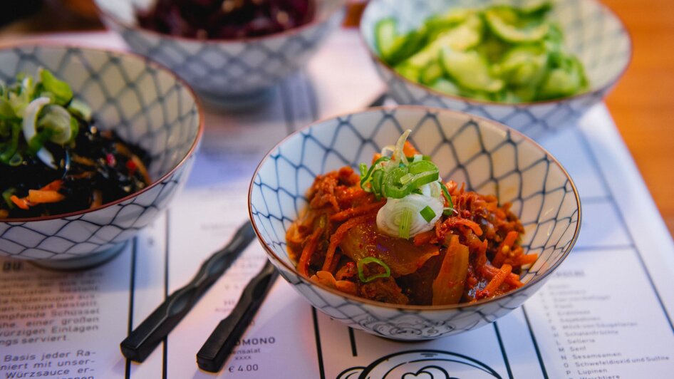 Schale mit Kimchi und Beilagen in einer Restaurantumgebung.
