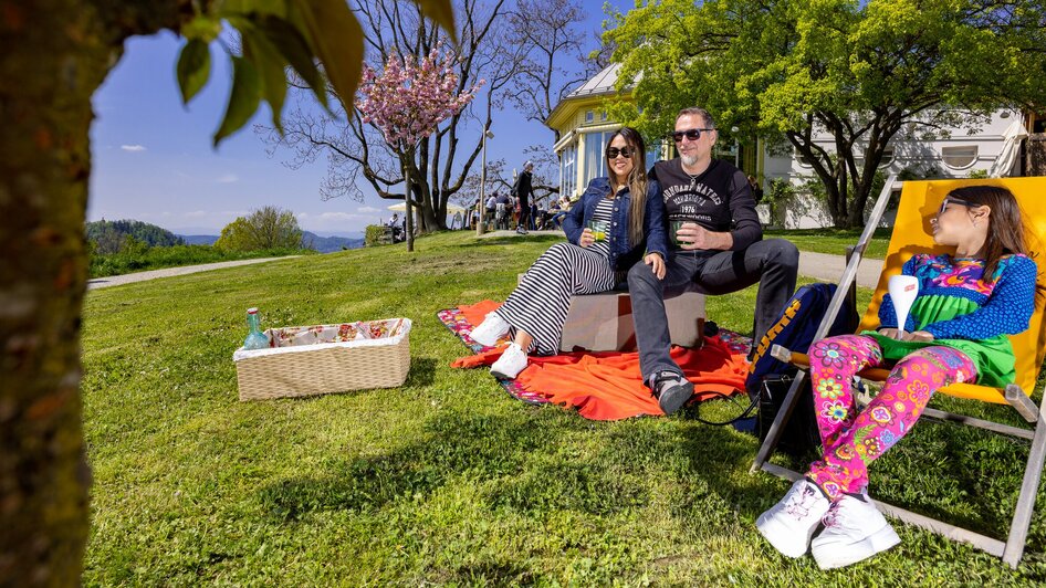 Familie genießt ein Picknick im Freien, umgeben von Natur.
