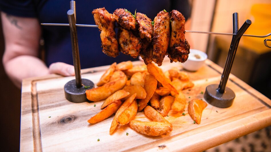 Ein Teller mit gegrillten Hähnchen und Kartoffelspalten.