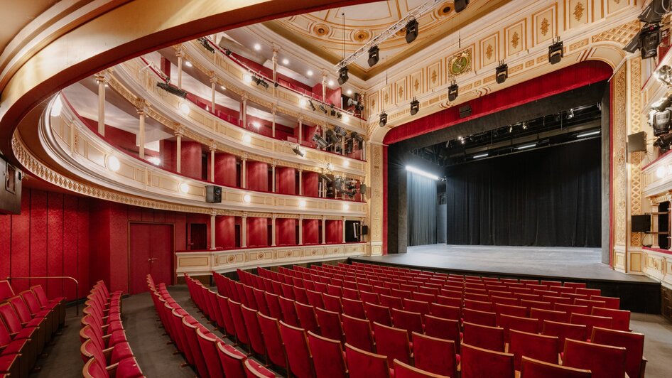 Blick ins Innere eines eleganten Theaters mit rotem Samt.