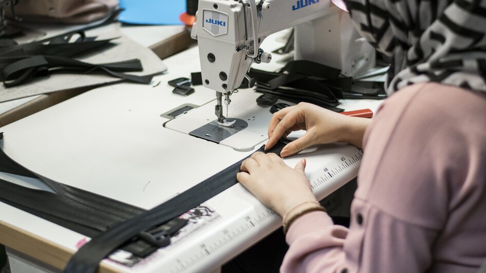 Eine Person näht an einer Juki Nähmaschine in einem kreativen Arbeitsumfeld.