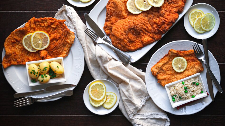Wiener Schnitzel mit Reis, Kartoffeln und Zitronenscheiben.