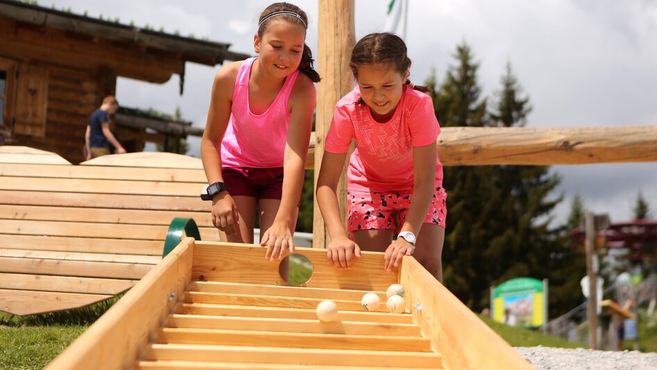 Kinder spielen mit der Kugelbahn.