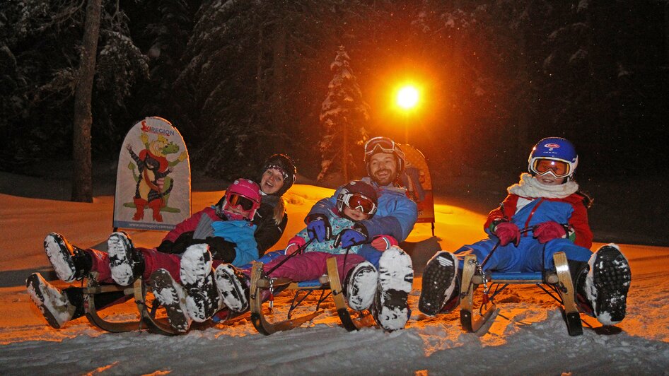 Familie auf Schlitten.  | © Hans-Peter Steiner