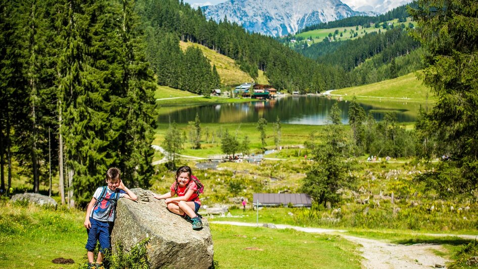 Kinder auf einem Stein vor dem Steirischen Bodensee